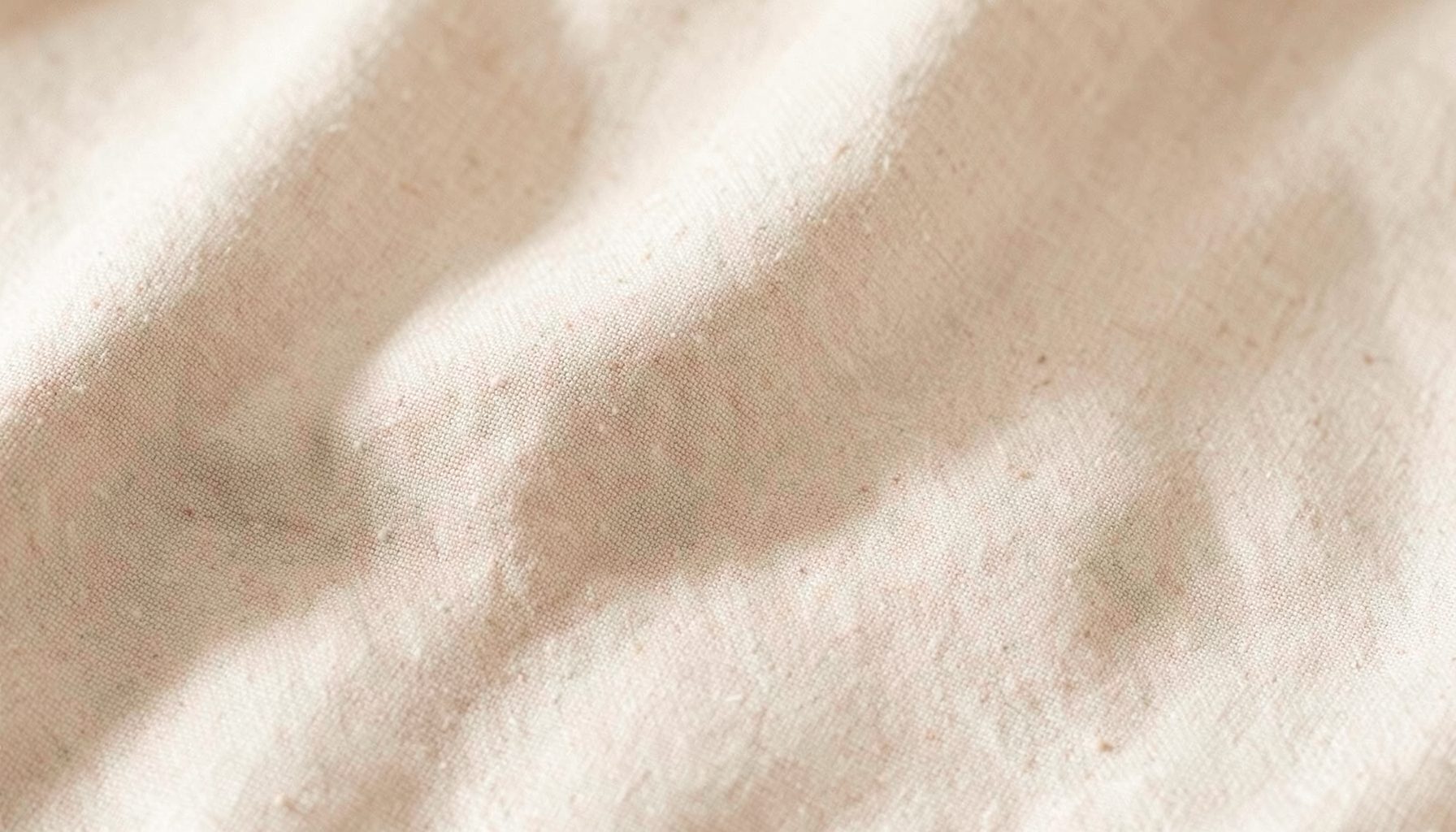 Soft neutral-toned fabric texture with warm beige and cream hues, relaxed lifestyle mood